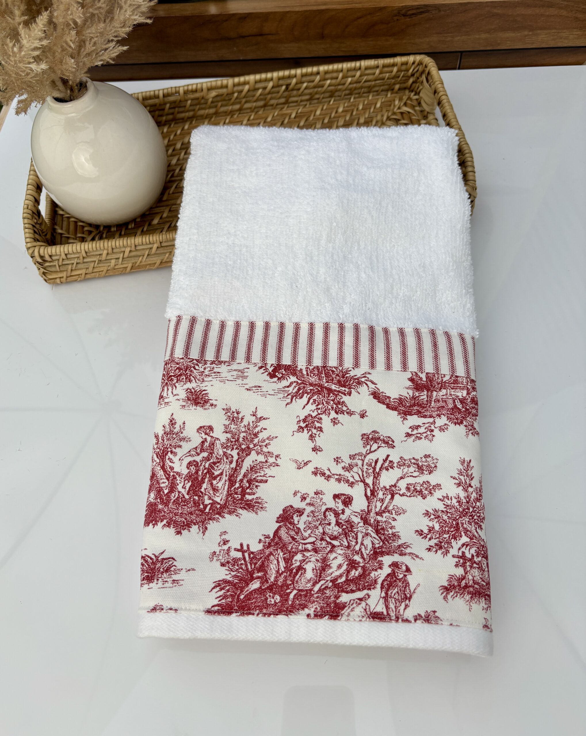 Decorative toile hand towel in woven basket on farmhouse bathroom counter