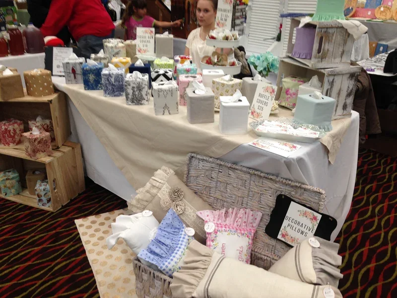 Craft fair booth table display of handmade tissue box covers and ruffle covers by Christy Crafted Covers