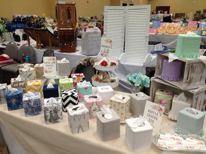 Craft fair booth full display of handmade tissue box covers pillows and home decor by Christy Crafted Covers