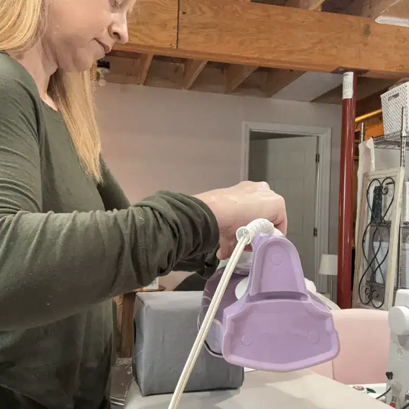 Woman pressing handmade tissue box cover with iron for perfect finish in sewing studio