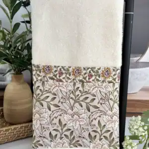 Close up of the sewn vintage floral fabric trim on a cream bathroom hand towel, neat handmade stitching