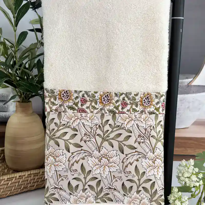 Close up of the sewn vintage floral fabric trim on a cream bathroom hand towel, neat handmade stitching