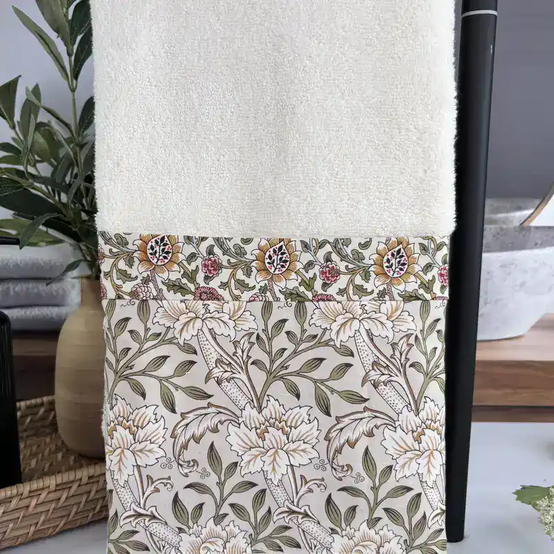 Cream decorative hand towel with a vintage floral fabric band, hanging in a farmhouse bathroom