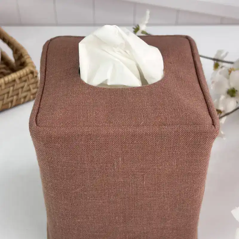 Top view of a brown linen tissue cover showing the finished oval opening and neat piped edges