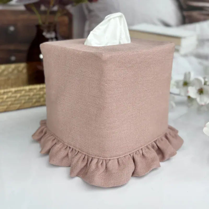 Dusty mauve pink ruffle tissue box cover in soft linen on a square tissue box by a bedroom nightstand