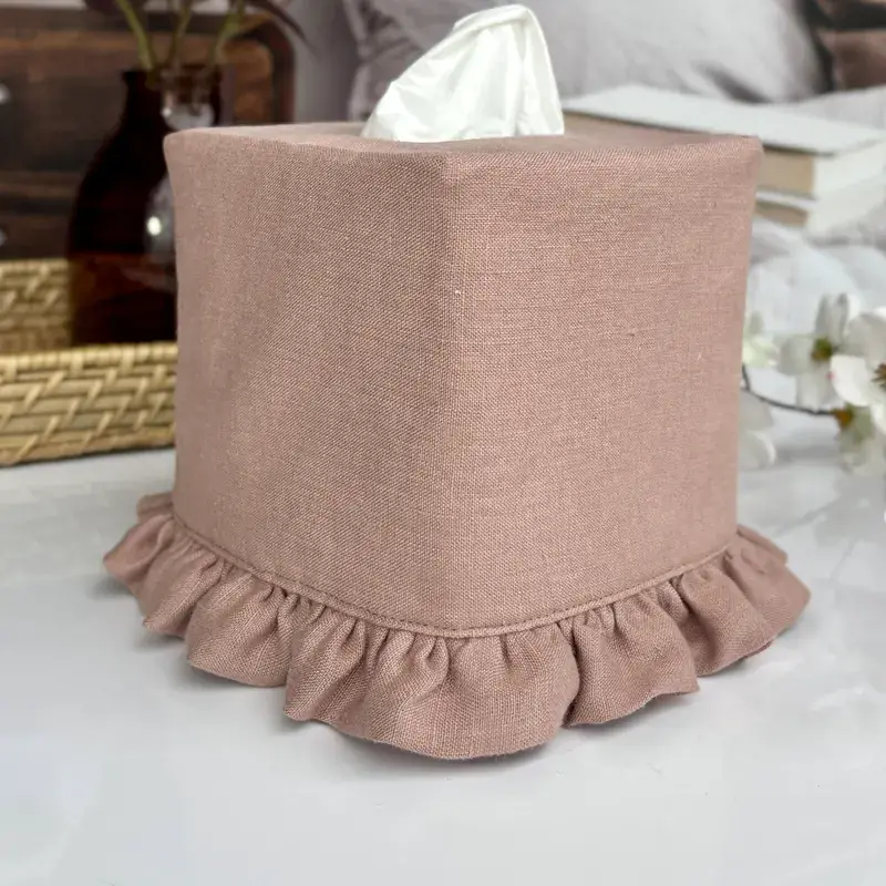 Handmade mauve linen tissue holder with ruffle trim on a nightstand, proudly made in the USA